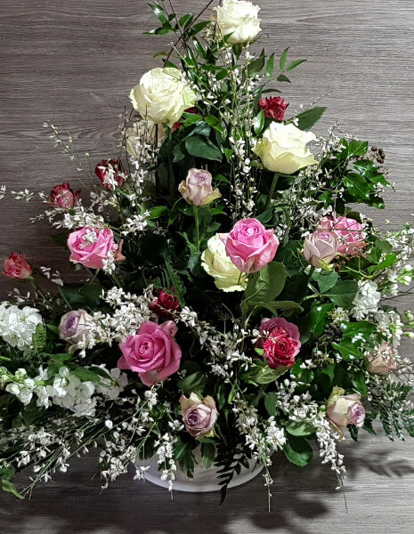 Composizione in cesto di rose colori tenui e verdi di decorativi